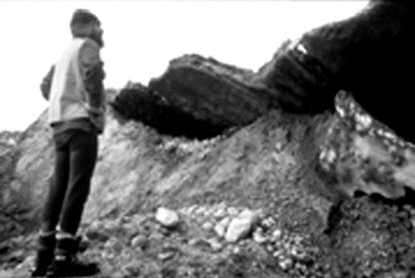 A hanging glacier terminus with a researcher standing under the cliff-like terminus