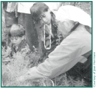 Lena Charley showing Zach and Karl Martin how to gather spruce roots.