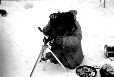 A close up of the same researcher photographing glacier ice crystals. 