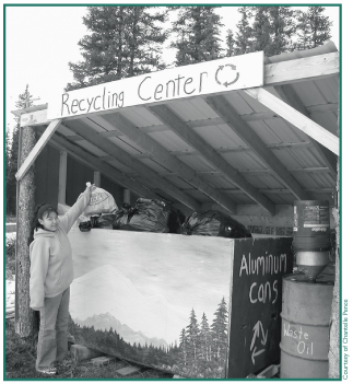 Angela Nicolai drops a bag of aluminum cans into the community bin for recycling