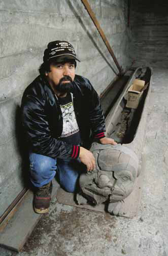 Bill Thomas poses with the deteriorating woodworm feast dish in the Whale House in Klukwan.