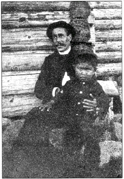 George Emmons holds Louis Shotridge in Front of a log wall in about 1885.